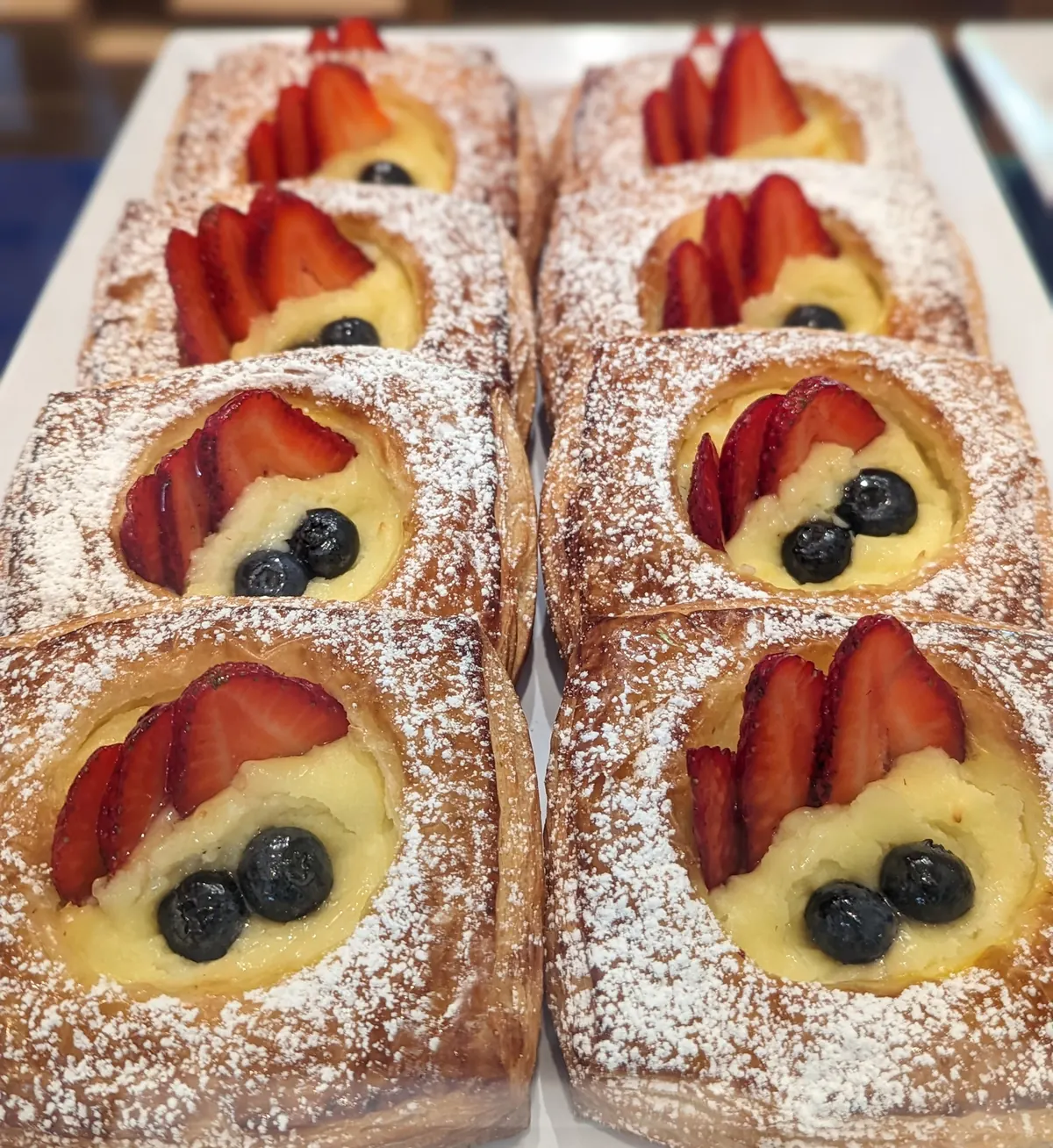 Danish pastries topped with custard, strawberries and blueberries