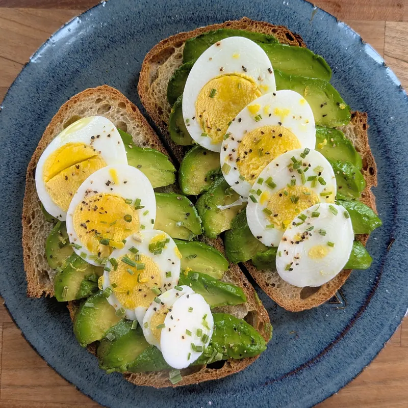 Avocado toast on house-baked bread topped with sliced hard-boiled eggs