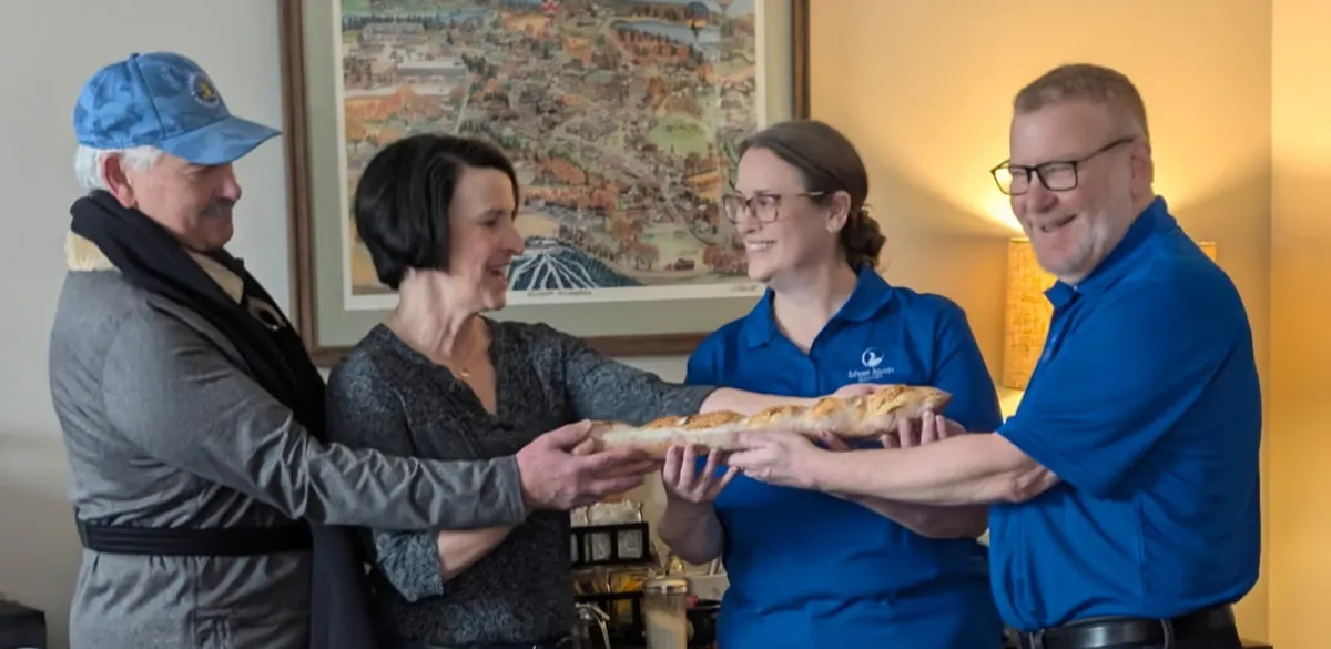 Four people smiling inside the bakery as they hold a loaf of Blue Loon bread together