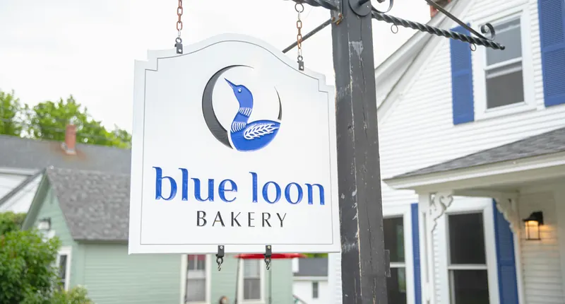 The Blue Loon Bakery sign, with its loon logo, hanging outside the shop