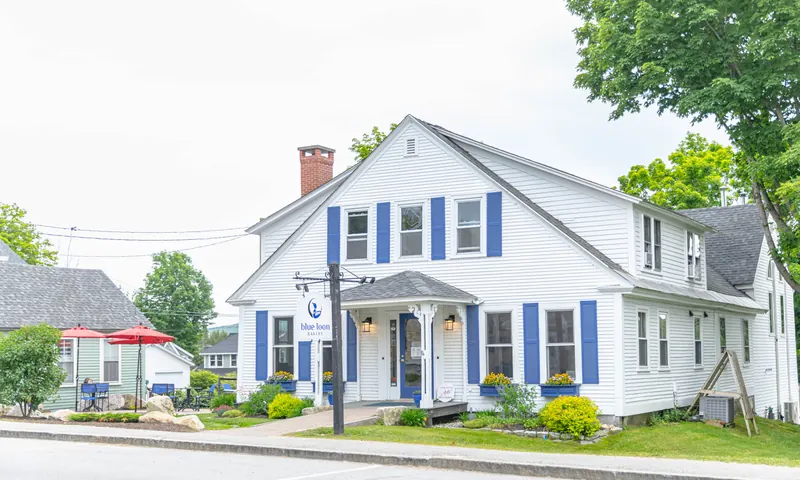 Blue Loon Bakery: a white clapboard house with blue shutters, red patio umbrellas and outdoor tables